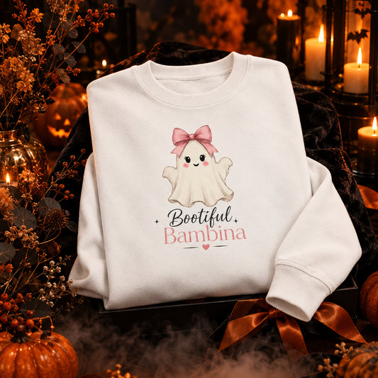 A white crewneck sweatshirt featuring a cute cartoon graphic of a baby ghost with a pink bow and the text 'Bootiful Bambina' printed on the front.
