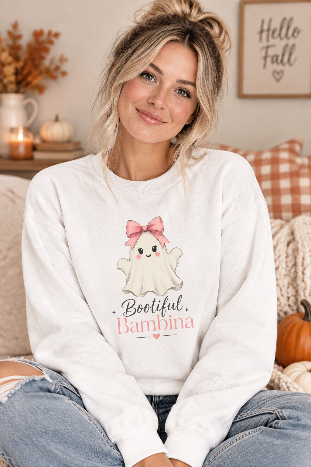 A white crewneck sweatshirt featuring a cute cartoon graphic of a baby ghost with a pink bow and the text 'Bootiful Bambina' printed on the front.