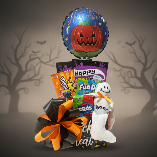 A Halloween-themed gift basket filled with assorted candy, a plush ghost, and a large black and orange bow, topped with a round foil balloon featuring a jack-o'-lantern and the words 'Happy Halloween'.